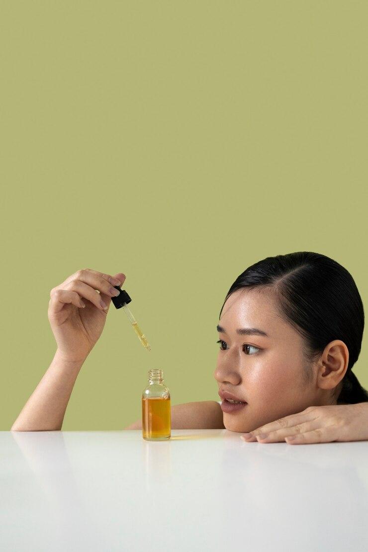 ขวดออยล์วางบนพื้นไม้ข้างกระปุกครีม สำลีจัดเรียงไว้อย่างเรียบร้อยใกล้กัน